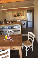 Modern Kitchen with flat top stainless steel stove and fridge. Dining table in foreground with Shells and flowers on table.