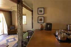 View of kitchen counter with bar stool and partial view of living room in background.